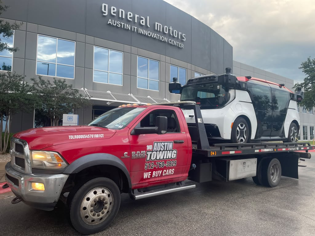 247 Austin Towing red flatbed tow truck loaded with a vehicle in Austin, Texas